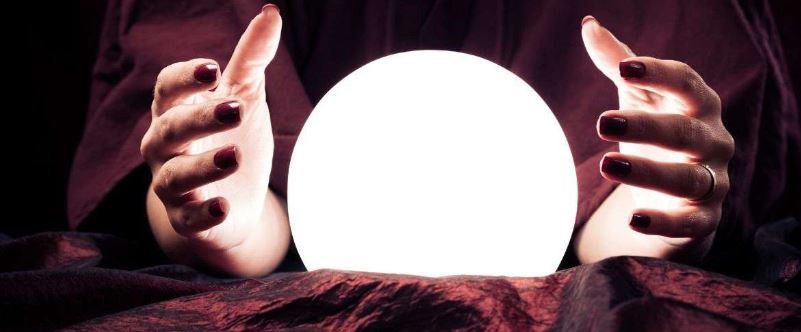 Image of A fortune teller waves her hands around a white glowing crystal ball